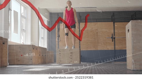 Red line graph image over woman standing on wooden box in gym. Fitness, workout, exercise, data, training, strength - Powered by Shutterstock