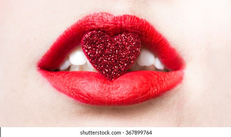 Red lips close up with a red sparkle heart in mouth