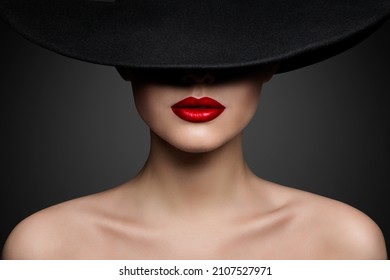 Rote Lippen machen Nahaufnahme. Mysteriöses Modeschaum Frauengefühl versteckt durch schwarz gepressten Hut. Elegantes Retro Lady Fine Art Portrait auf grauem Hintergrund