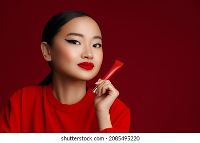 Red lipstick. Attractive young korean model with red lips make up posing with beauty product