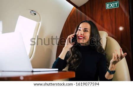Red lipstick. Close-up photo of a pro-active girl in a fashionable outfit, who is talking on the phone and gesticulating during her flight.