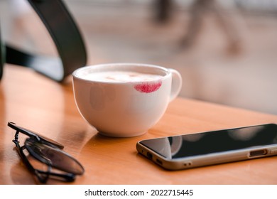 Red Lipstick Mark On A Coffee Cup On The Table In Cafe