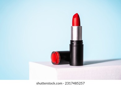 Red Lipstick on white podium at blue background. Makeup, cosmetic product.