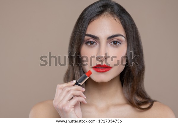Red lipstick. Serious\
beautiful face of dark haired woman with brown eyes with red\
lipstick on her lips