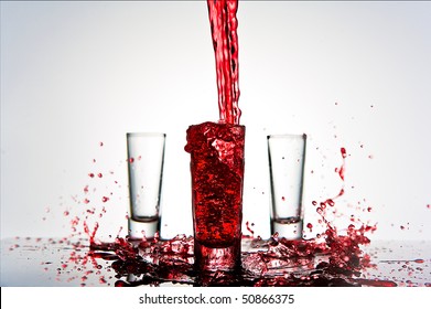 Red Liquid Splashes Into Shot Glass