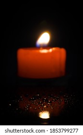 Red Lit Candle Or Reflective Wet Surface