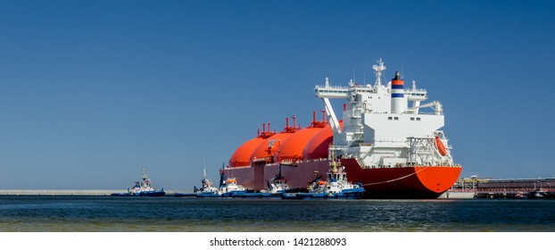 RED LNG TANKER AND SWARM OF TUGBOATS - A giant ship moored to the gas terminal in Swinoujscie