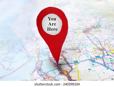 Red locator symbol on a map with You Are Here text                              