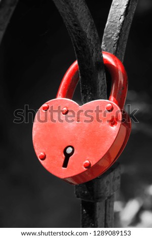 Red lock in the shape of a heart hangs on the railing. Monochrome Background