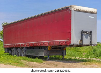 Red Lorry Cargo Trailer Parked At Grass Field