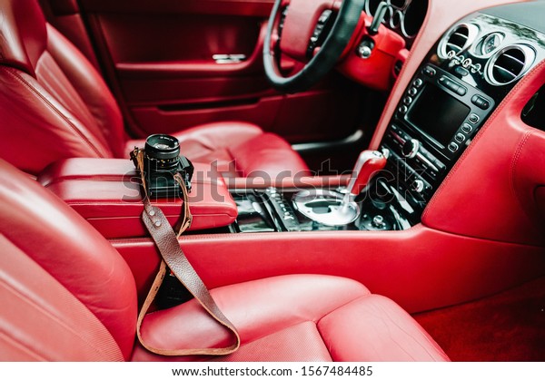 Red luxury car interior -\
dashboard with gauges, steering wheel and shift lever. Modern car\
inside. Comfortable leather red seats. Details. Camera in the\
car.