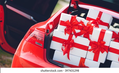 Red Luxury Car With Trunk Full Of Gift Boxes. Presents For Holiday. Car, Presents. Holidays, Happiness. Street Outdoor 