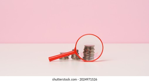 Red Magnifier And White Coins On The Table. Income Growth Concept, High Percentage Of Investment. Search For New Sources Of Income, Subsidy