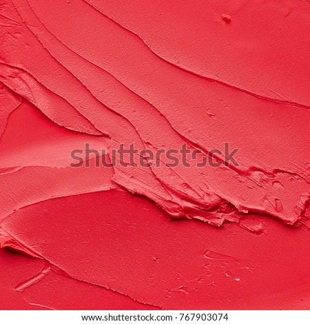 Red makeup smears of lip gloss  background. Broken red cream lipstick texture background