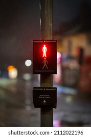 Red Man Stop Sign Illuminated At Night On Traffic Light Zebra Crossing With Road And Streetlights Out Of Focus Behind. Pedestrians Waiting For Green Man To Show In Rain And Dark.