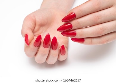 Red Manicure On Long Sharp Nails Closeup On A White Background. Red Stilettos. Gel Nails.