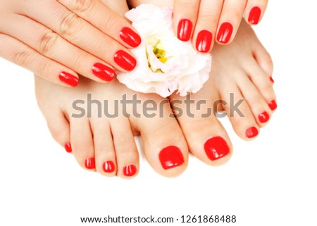 Red manicure and pedicure with flower close-up, isolated on white background