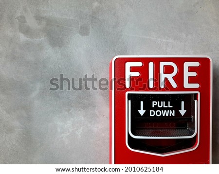 the red  manual station of the fire alarm system on the grey wall.