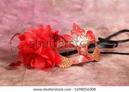Red mask with feathers on colored background