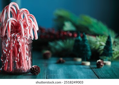 Red mason jar tied with a twine and filled with peppermint candy canes. Christmas decor and branches in back. Selective focus with blurred background. - Powered by Shutterstock