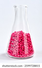 Red masterbatch granules in Erlenmeyer flask isolated on white background, color pigment carrier polymer in plastic industry. Perfect for plastic company catalog design