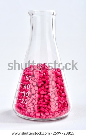 Red masterbatch granules in Erlenmeyer flask isolated on white background, color pigment carrier polymer in plastic industry. Perfect for plastic company catalog design