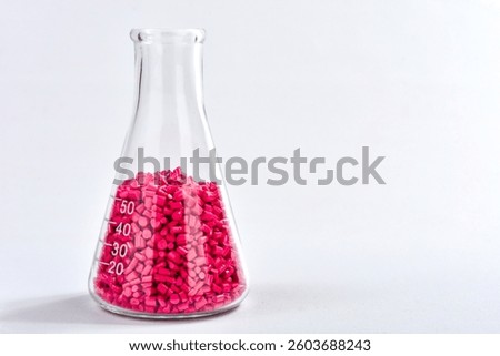 Red masterbatch granules in Erlenmeyer flask isolated on white background, color pigment carrier polymer in plastic industry. Perfect for plastic company catalog design