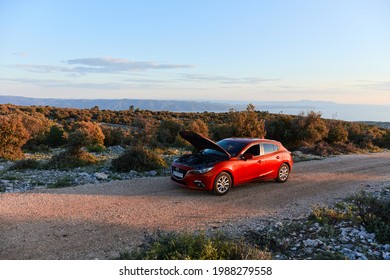 Red Mazda 3 With An Open Hood Is Standing During A Holiday Tour Of A Island. Sunset, No People. Brac Island, Croatia - 05.31.2019