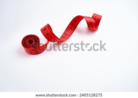 Red measuring tape on a white background. Tool for measuring length and volume. Tape for measuring in the clothing industry or the volume of the human body