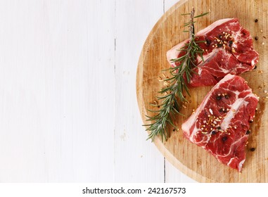 Red Meat And Rosemary Over White Wooden Background With Copy Space. Top View