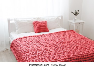 Red Merino Wool Blanket Or Plaid On Bed With White Linen. Blanket Of Thick Yarn. Chunky Knit. Bedroom Interior Decor.