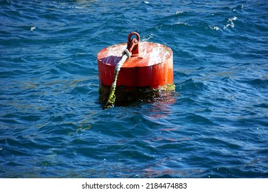 A red metal buoy for mooring ships and boats floating in the blue sea