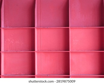 Red metal grid structure with rectangular patterns and shadows