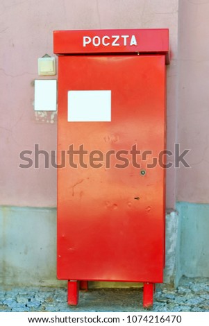 Red metal mailbox of national and international state Polish postal service stands at wall on paving stone. Letter box on main street of Bialystok, Poland