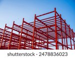 The red metal Structure of a large Industrial Building in the Construction Site