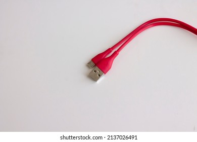 Red Micro Usb Charger For Handphone. Cable Phone Chargers On White Background. Red Cable With USB And Micro USB Connectors Isolated On A White Background. Smart Phone Charger Cables