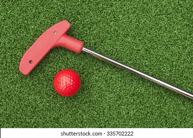 Red Mini Golf Putter And Ball Laying On Artificial Turf