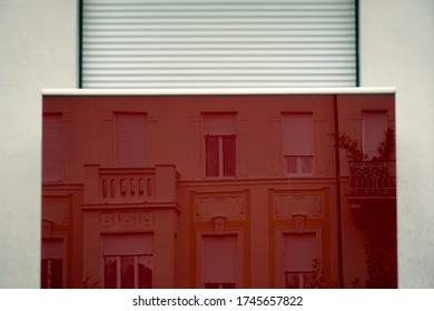 A red mirror with the building facade reflected in it