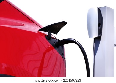 Red Modern Electric Car Charging At EV Charging Station Isolated On White Background. Environmental Green Energy Car Industry Background. Copy Space.