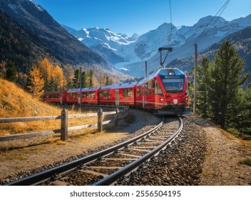 Red modern electric train traveling along a railway, winding through a stunning high mountains with snow-capped peaks and vibrant autumn trees in switzerland. Bernina Express in fall. Railway tourism