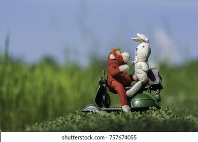 Red monkey doll with white rabbit doll on motorcycle toy in the field