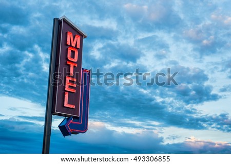 Red motel neon sign over a sunset cloudy sky