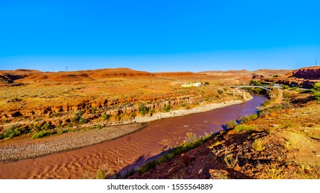 The Red Muddy San Juan River As It Flows Through The Red Sandstone Landscape Past The Settlement Of Mexican Hat At The Northern Edge Of The Navajo Nation's Borders In Southern Utah, United States