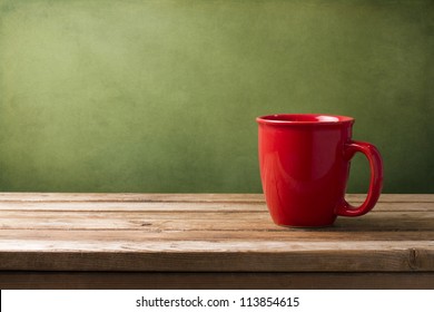 Red mug on wooden tabletop against grunge green wall - Powered by Shutterstock