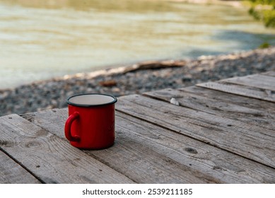 a red mug with tea or coffee stands on a bench against the background of mountains - Powered by Shutterstock