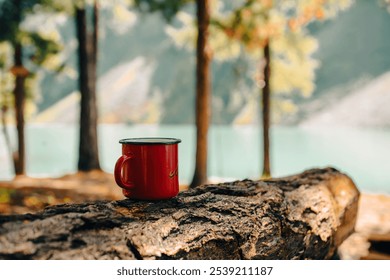 a red mug with tea or coffee stands on a bench against the background of mountains - Powered by Shutterstock