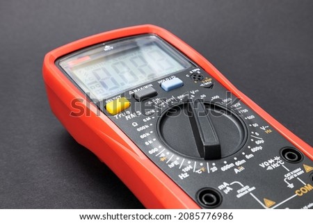 Red multimeter, multimeter or multitester, modern multifunctional voltage measuring instrument on dark background