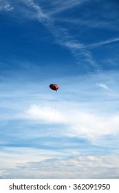 Red Mylar Heart Shaped Valentines Day Helium Filled Balloon Floats Freely Into The Blue Sky With White Clouds. Valentines Day Is Celebrated On February 14 Of Each Year.