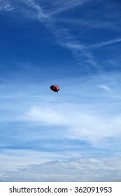 Red Mylar Heart Shaped Valentines Day Helium Filled Balloon Floats Freely Into The Blue Sky With White Clouds. 