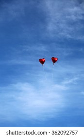 Red Mylar Heart Shaped Valentines Day Helium Filled Balloon Floats Freely Into The Blue Sky With White Clouds. Valentines Day Is Celebrated On February 14 Of Each Year.